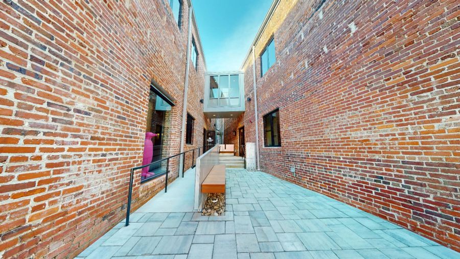 The brick-paved courtyard between two historic buildings, with the glass bridge spanning overhead
