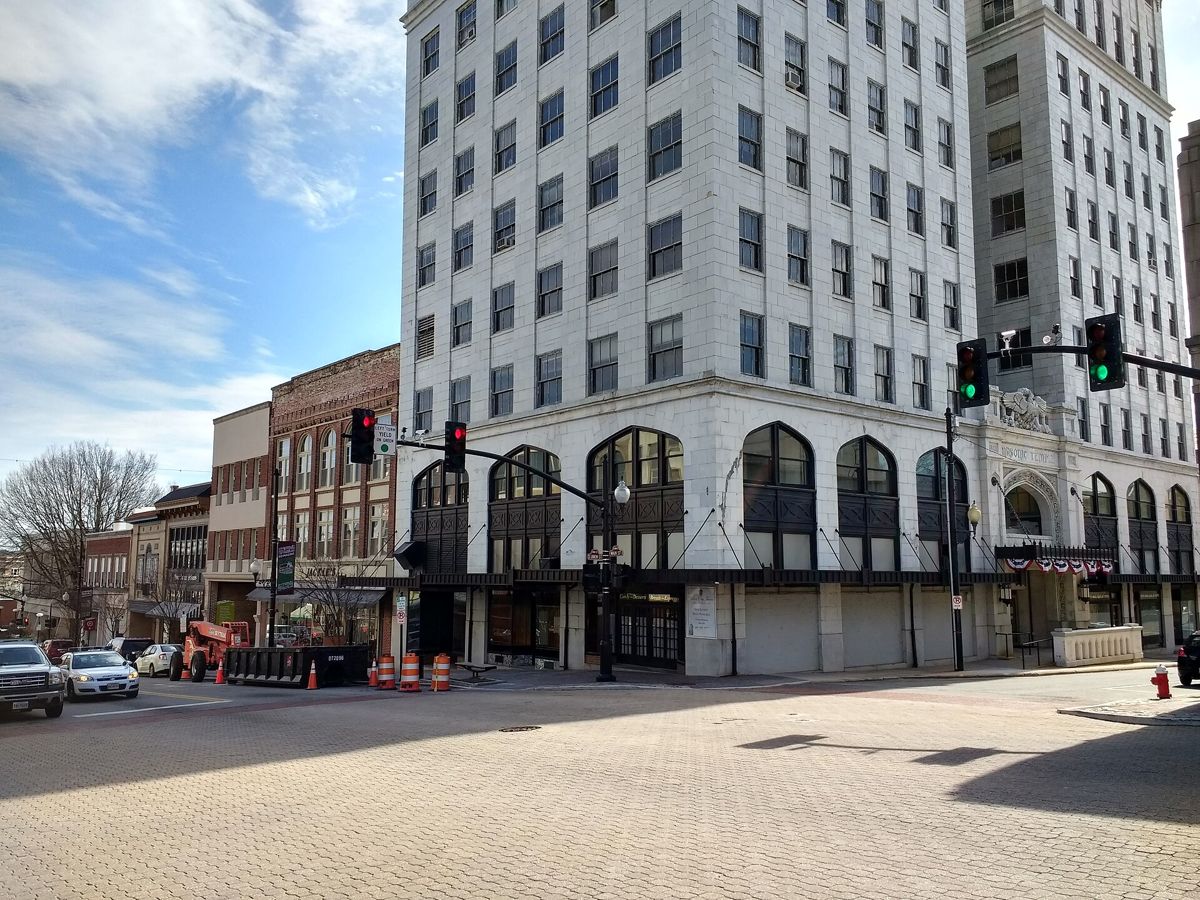 The white terra-cotta Masonic Temple and a row of brick storefronts at a brick-paved intersection in downtown Danville
