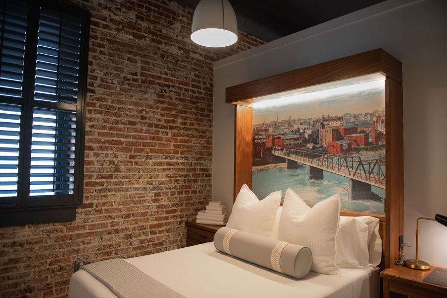 Bedroom with exposed brick and a backlit mural of the Danville river bridge