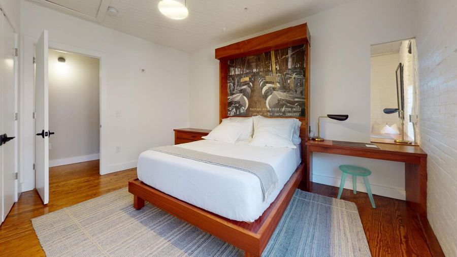 Bedroom with a sapele headboard framing a historic photograph of the Riverside and Dan River Cotton Mills