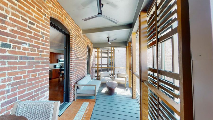 Screened rear porch with exposed brick, wood slat screens, ceiling fans and outdoor seating
