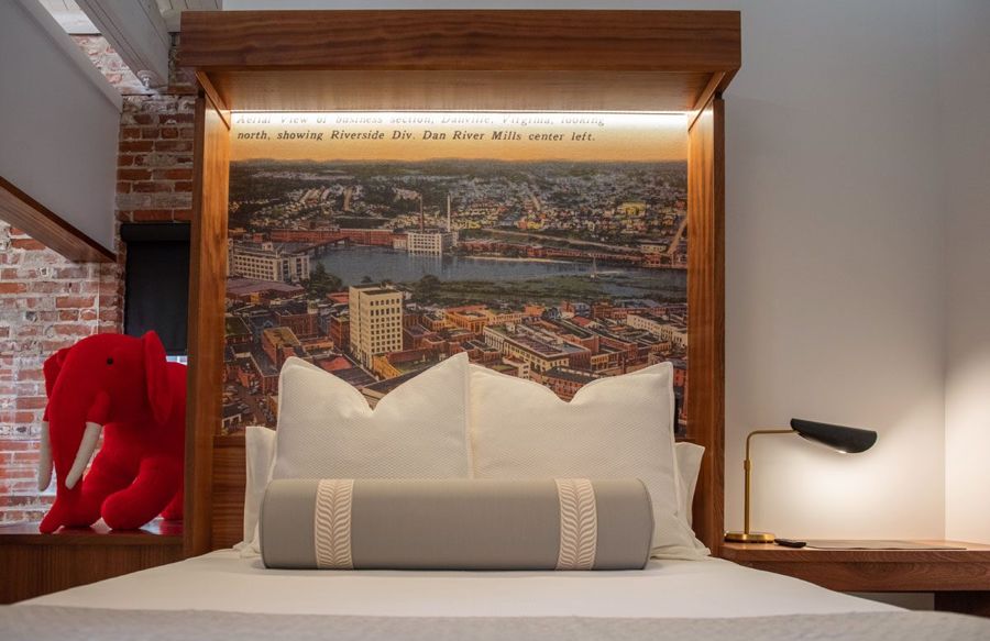 Straight-on view of the bed and its backlit vintage aerial postcard of downtown Danville and the Dan River