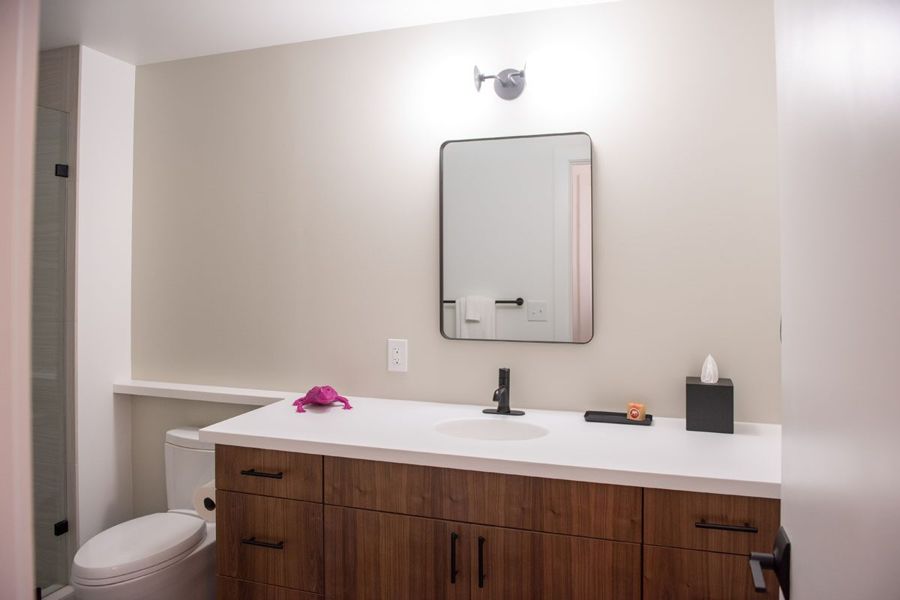 Bathroom vanity with a sapele wood cabinet, white counter and black-framed mirror