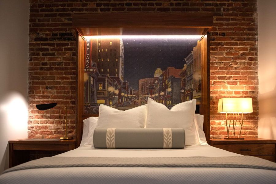 Bed with a backlit headboard framing a vintage postcard of a Danville street at night, flanked by sapele nightstands